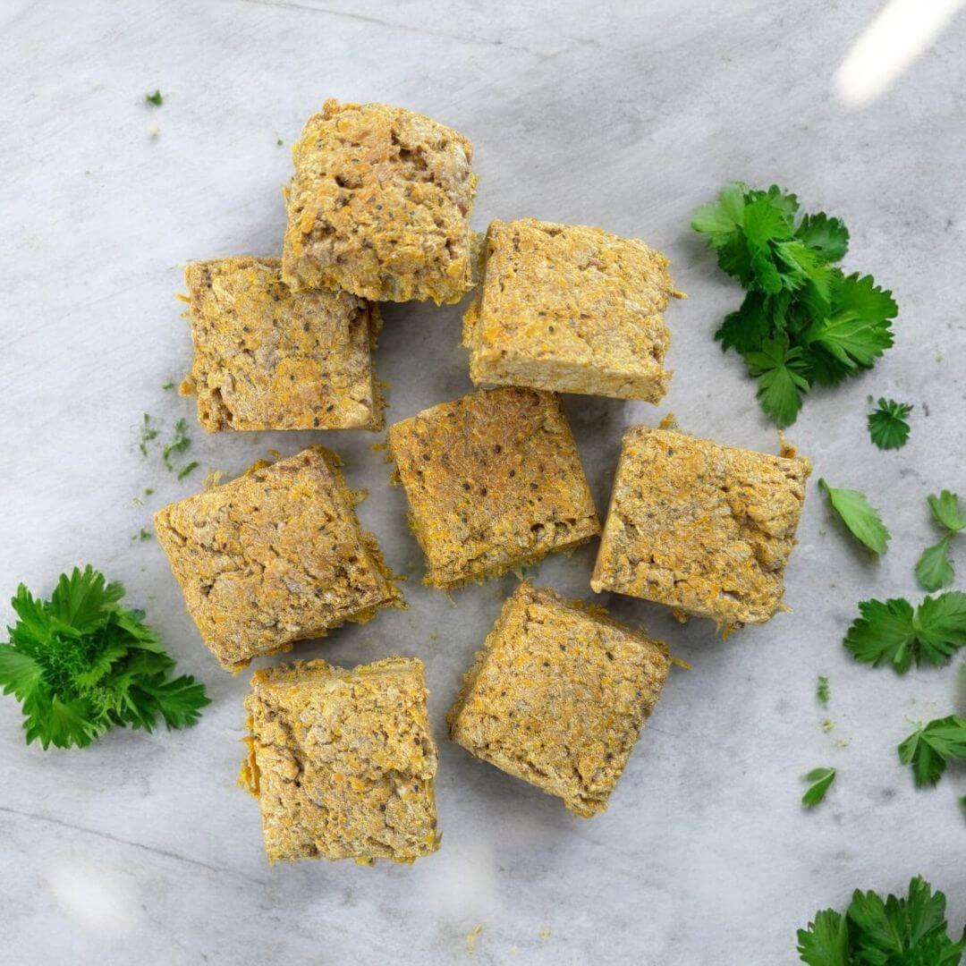 Freeze dried pork treats for pets arranged on a marble surface with fresh cilantro.