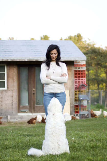 Photo of a woman wth a white dog sitting in front of her.