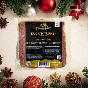 Packaged raw duck and turkey dog food with Carnevore label on a festive background with Christmas decorations.