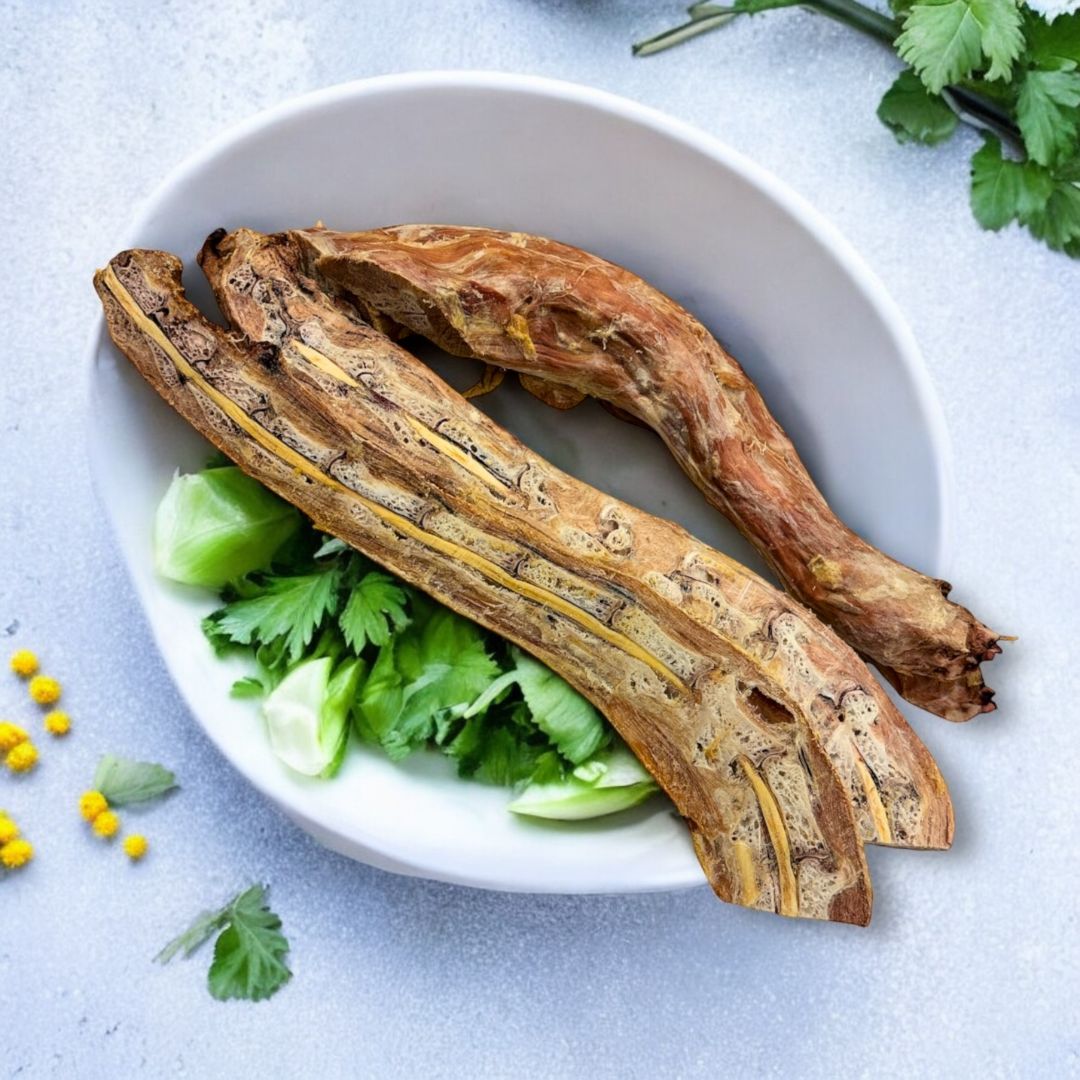 Picture of turkey necks which have been cut in half and then freeze dried.  They are placed in a white bowl with parsley.  The background is textured and has yellow flowers. 